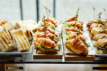 Professional catering display of a traditional afternoon tea service featuring tiered platters of sandwiches, scones,